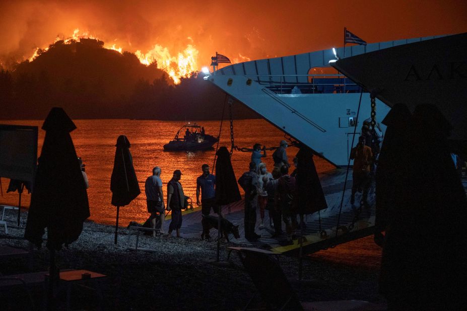 People are evacuated on a ferry as a wildfire burns in Limni, Greece, on August 6.