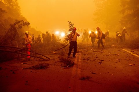 Firefighters battling the Dixie Fire clear a fallen tree from a roadway in Plumas County, California, on August 6.