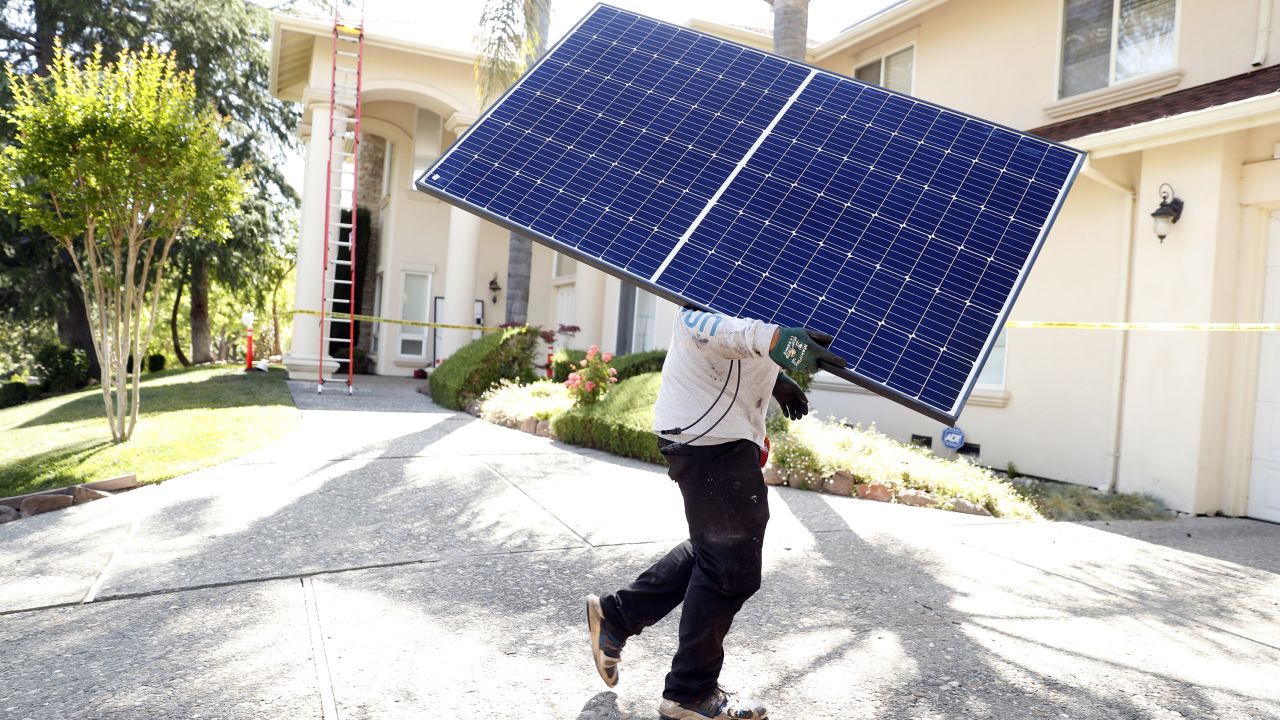 A Sunrun employee carries a solar panel to an installation at a home in California in May.