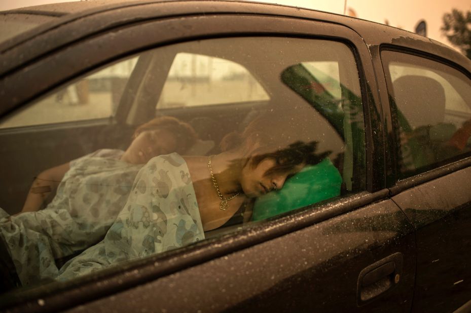 People sleep in a car near the beach in Pefki village as wildfires rage on the island of Evia on August 8.