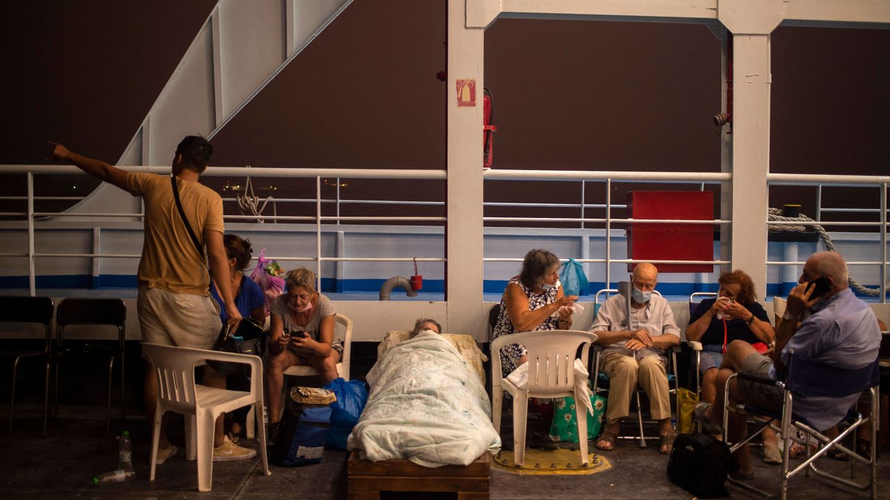 Elderly people are seen on chairs and makeshift bed onboard a ferry at the port of the village of Pefki, during a wildfire at Pefki village on Evia.
