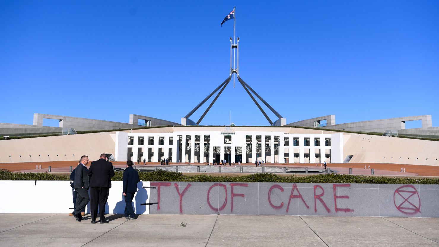 Workers cover the slogan 'Duty of Care' after an Extinction Rebellion protest outside Parliament House, in Canberra, Monday, August 10.