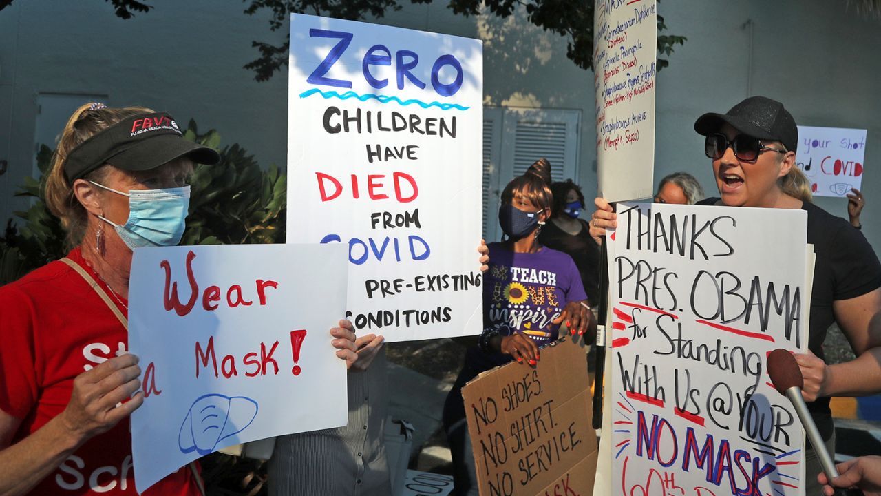 Anti-mask advocate Heather Tanner, right, tries to persuade Mary Tereilleger, who teaches three-year-olds in Broward County's Head Start program, that students do not need to wear masks when they return to school during a protest outside of a Broward County School Board meeting, Tuesday, Aug. 10, 2021, in in Fort Lauderdale, Fla., to discuss a possible mask mandate when school starts next week. (Amy Beth Bennett/South Florida Sun-Sentinel via AP)