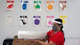 Wearing a face mask and shield to protect against the spread of COVID-19, kindergarten teacher Judith Ramos prepares her classroom, Thursday, Aug. 13, 2020, in San Antonio. Southside will being the year with remote teaching and has added hotspots to the school district to help students without access to the internet. (AP Photo/Eric Gay)