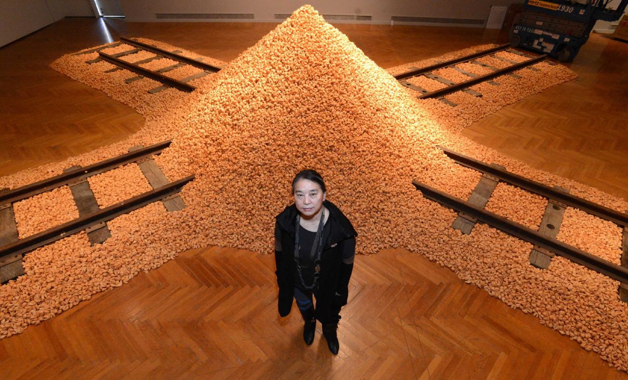 Hung Liu stands in front of her 1994 work consisting of 200,000 fortune cookies atop the crossroads of railroad tracks entitled Jiu Jin Shan (Old Gold Mountain) at Mills College in Oakland, California.