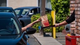 An employee wearing a protective glove hands an order to a customer at a Wendys Co. restaurant in Richmond, California, U.S., on Wednesday, May 6, 2020. 