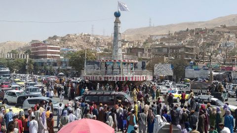 A Taliban flag is seen on a plinth with people gathered around the main city square at Pul-e-Khumri on August 11, 2021 after Taliban captured Pul-e-Khumri, the capital of Baghlan province.