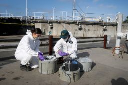 Gabriela Esparza and Zach Wu, wastewater control inspectors with EBMUD, cap 24 separate bottles while retrieving collection equipment and the samples in Oakland, California, in July 2020. The samples are sent to labs to detect coronavirus in the sewage.