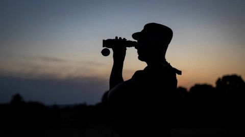 A member of the Lithuania State Border Guard Service looks through binoculars as he patrols on the border with Belarus, near the village of Purvenai, Lithuania.