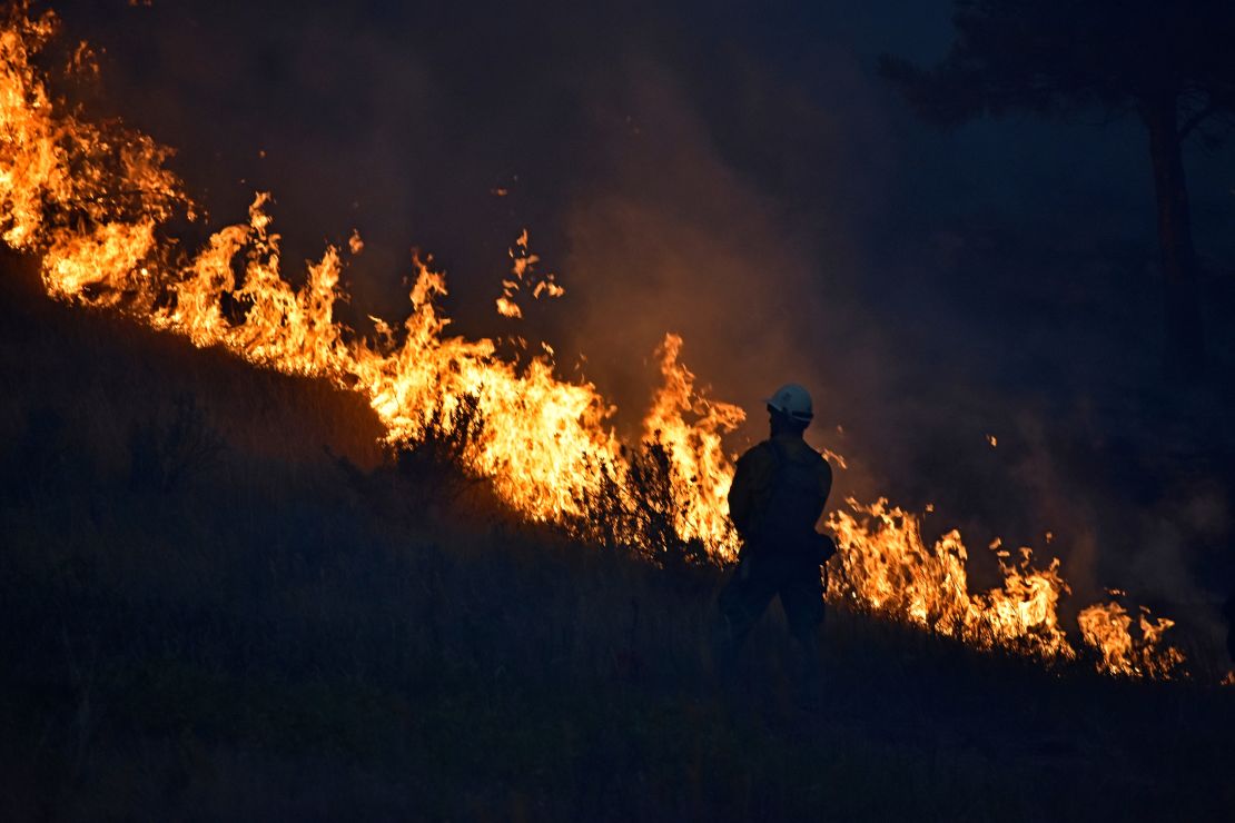 A firefighter stands along the edge of the wildfire burning on the Northern Cheyenne Indian Reservation on  Aug. 11, 2021. 