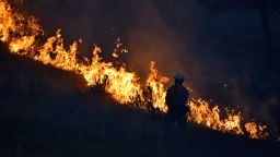 A firefighter stands along the edge of a wildfire burning on the Northern Cheyenne Indian Reservation, Wednesday, Aug. 11, 2021. In southeastern Montana, communities in and around the Northern Cheyenne Indian Reservation were ordered to evacuate as the Richard Spring Fire grew amid erratic winds. 