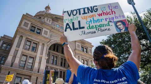 In this July 31, 2021, file photo, people display signs during the Georgetown to Austin March for Democracy rally in Austin, Texas. 