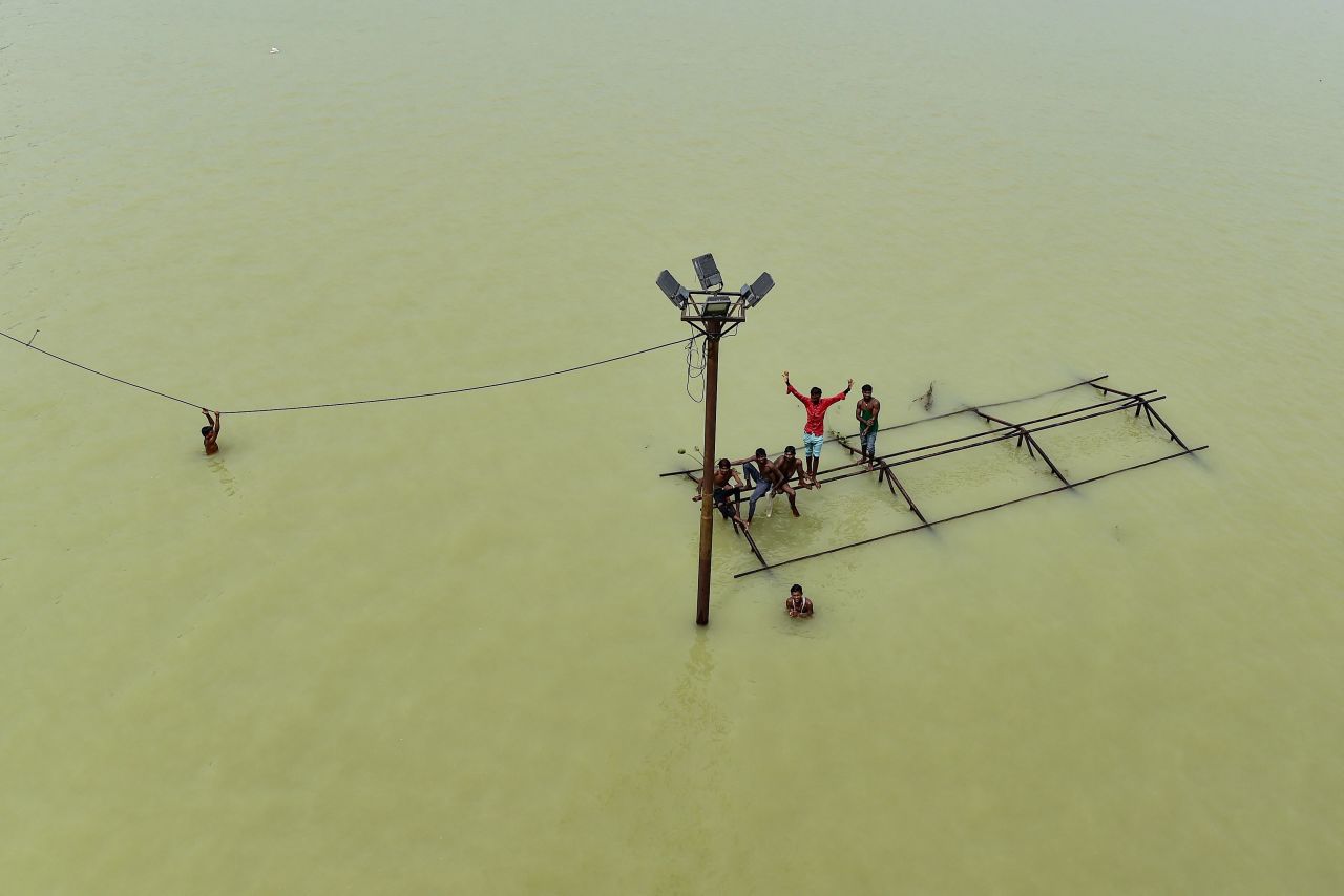 Boys and local boatmen play atop a submerged structure at Daraganj Ghat, one of the flooded banks of the Ganges River in Prayagraj, India, on Sunday, August 8.