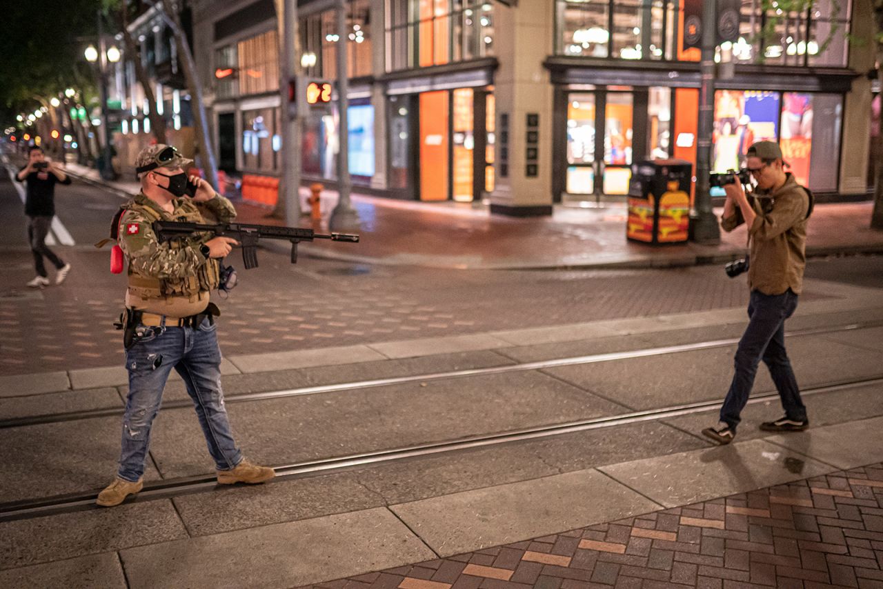 A right-wing protester points a weapon at journalist Justin Yau, who was covering clashes between right-wing protesters and anti-fascist protesters in Portland, Oregon, on Sunday, August 8. Police later determined the weapon to be an airsoft gun, <a href="https://www.oregonlive.com/crime/2021/08/portland-police-no-show-as-rival-factions-brawl-right-wing-militant-aims-replica-assault-rifle.html" target="_blank" target="_blank">according to The Oregonian,</a> but that was not known at the time it was aimed at Yau. The toy replica guns shoot plastic pellets and are designed to be nonlethal.