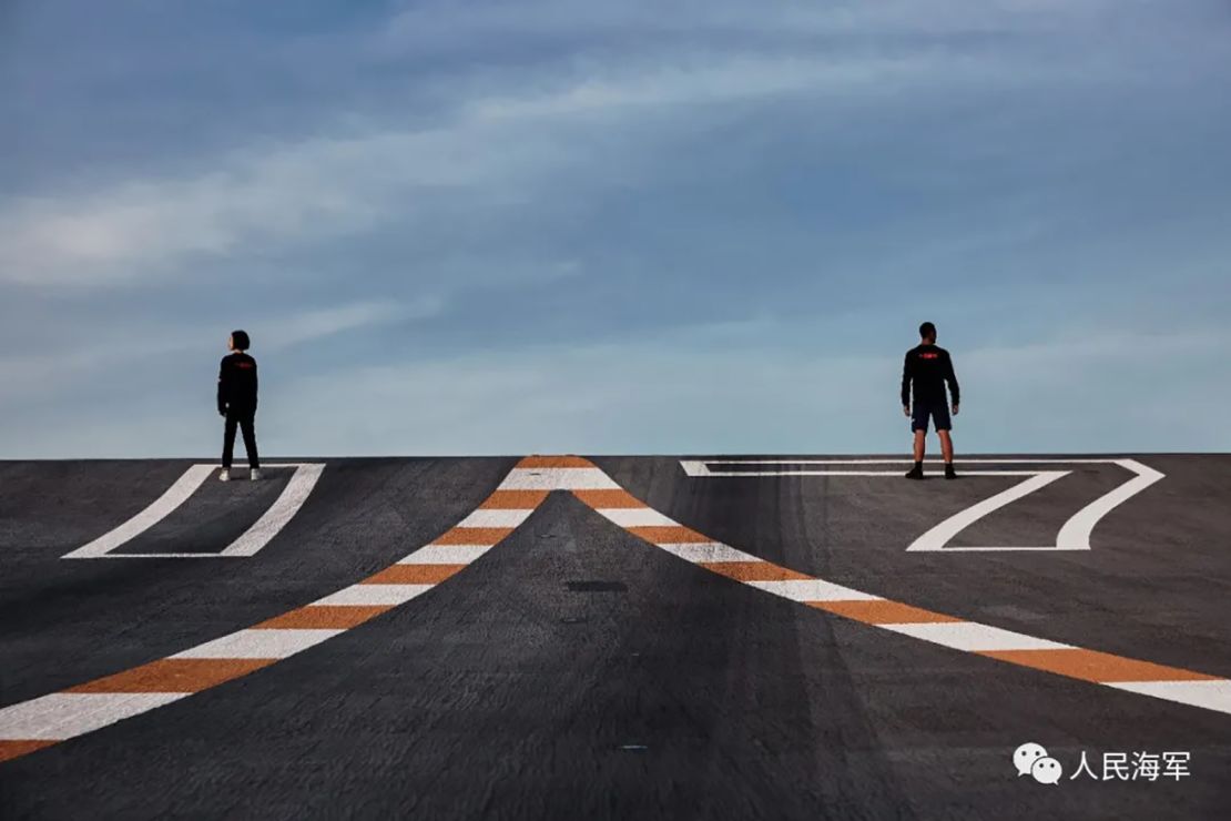 A photo shoot sees models posing on the aircraft carrier's launch ramp.