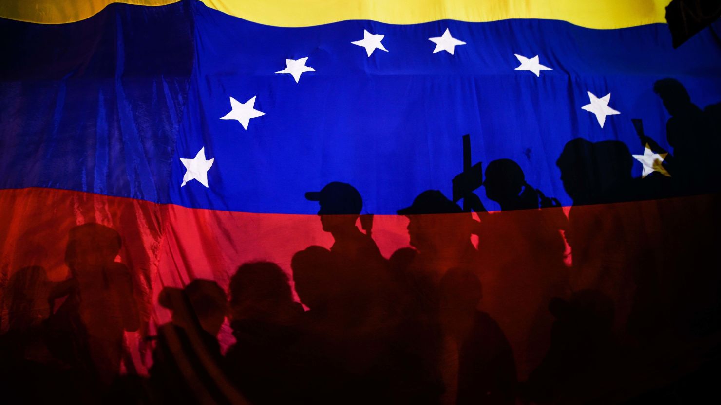 Opposition activists, seen here behind a Venezuelan flag, protest against the deaths of 43 people in clashes with the police during weeks of demonstrations against the government of Venezuelan President Nicolas Maduro, in Caracas on May 17, 2017. 