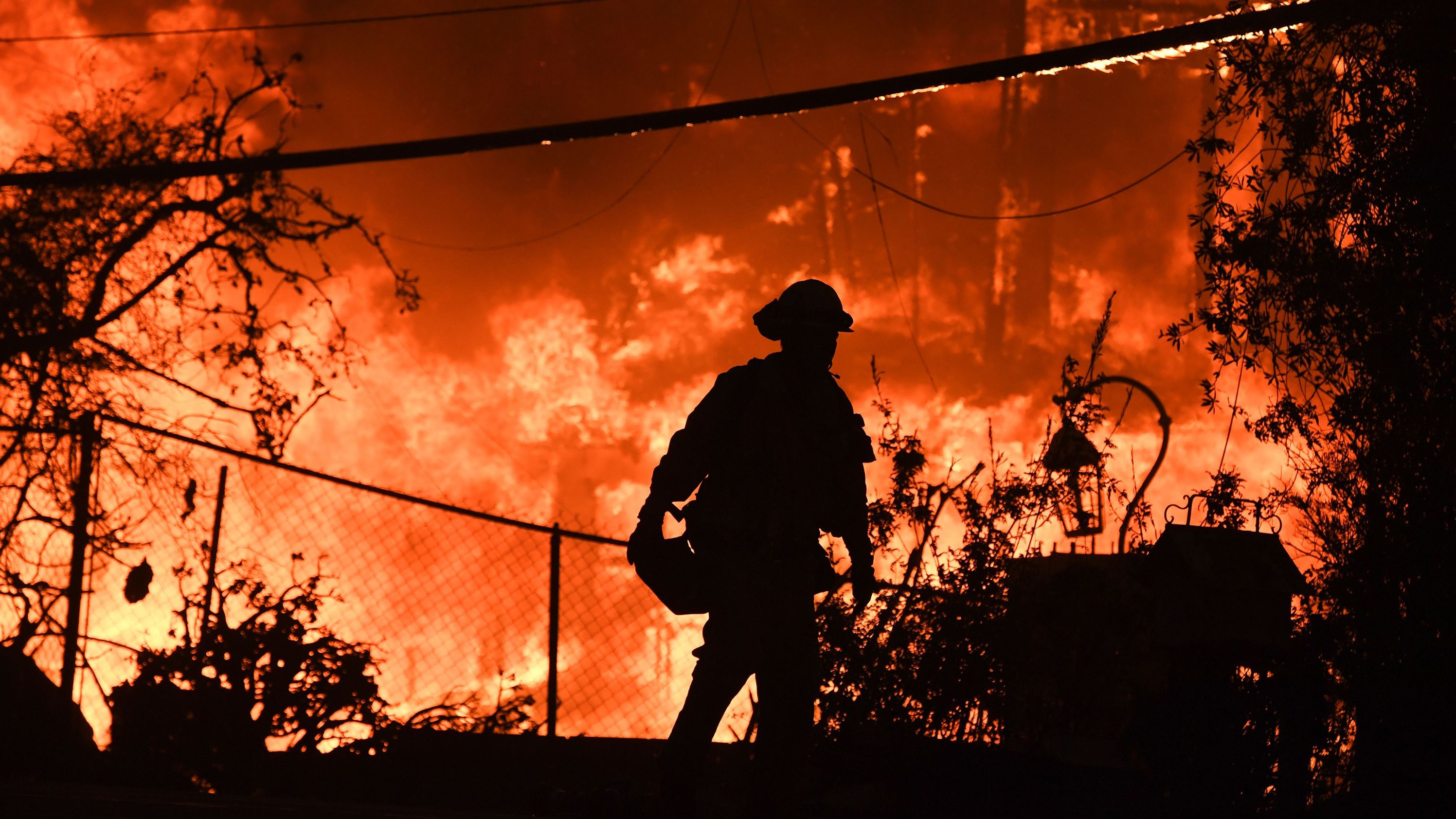 A firefighter is silhouetted by a burning home along the Pacific Coast Highway during the Woolsey Fire on November 9, 2018, in Malibu, California.