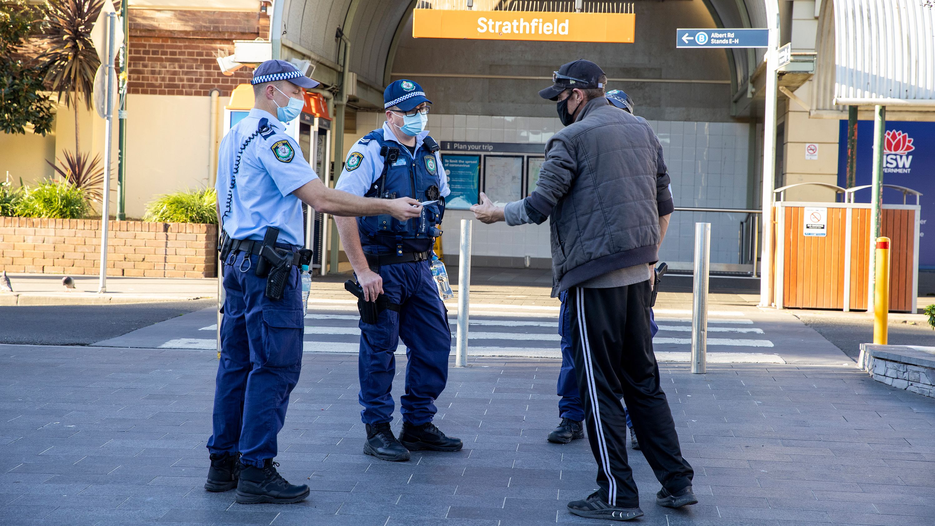Police officers approach a man for not wearing a mask at Strathfield station, Sydney, on August 12.