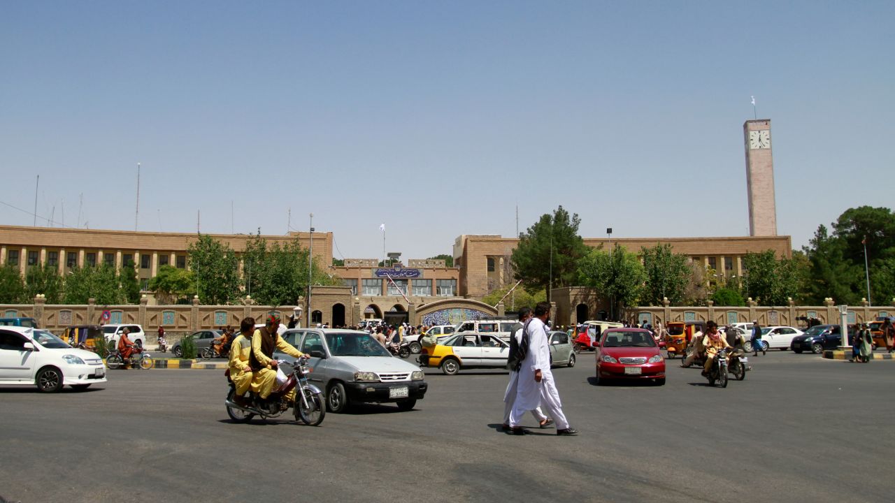 Pedestrians and motorists travel near the Herat provincial official office, Saturday, after the province was taken by the Taliban several days before.