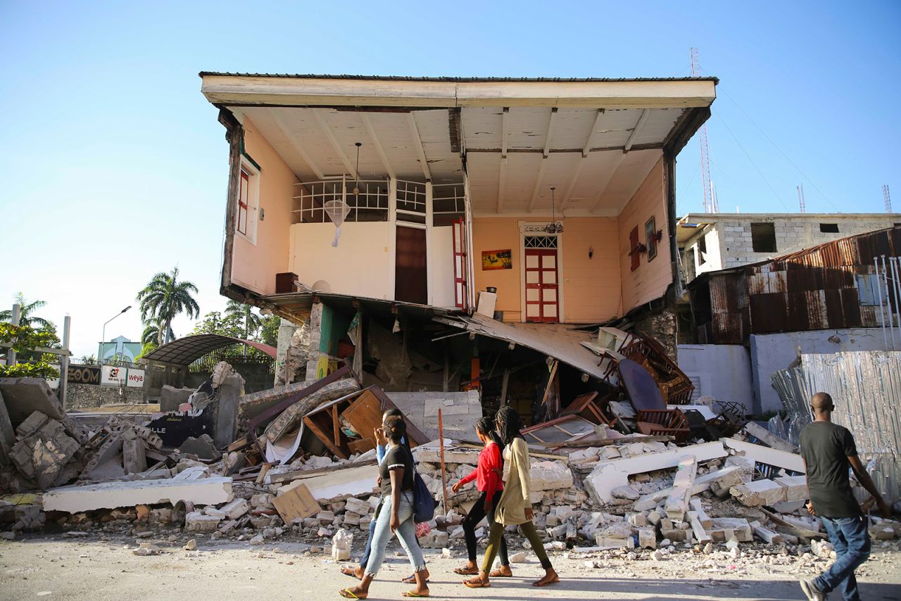 People walk past a Les Cayes home on August 14.