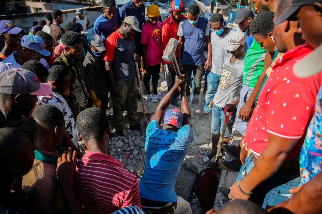 A man uses a sledgehammer in an attempt to rescue people from the remains of a home in Les Cayes on August 14.