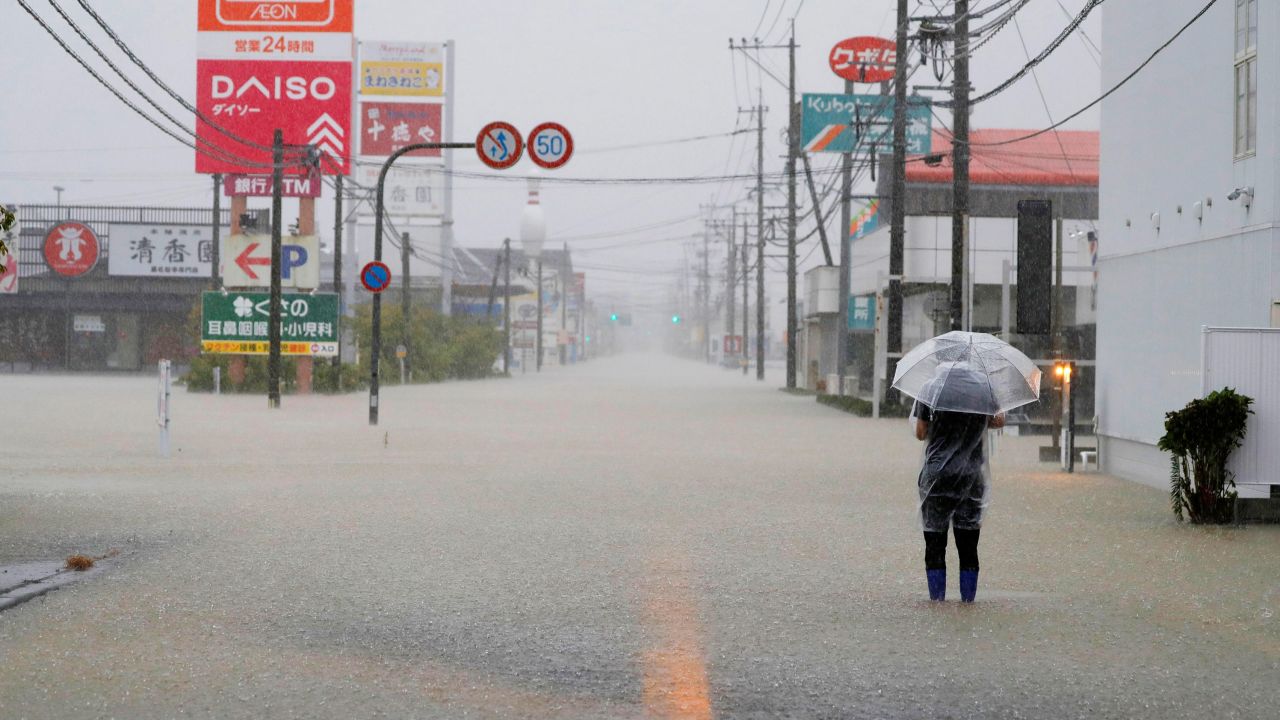 A man walks on a road flooded by heavy rain in southwestern Japan's Saga Prefecture on Saturday.