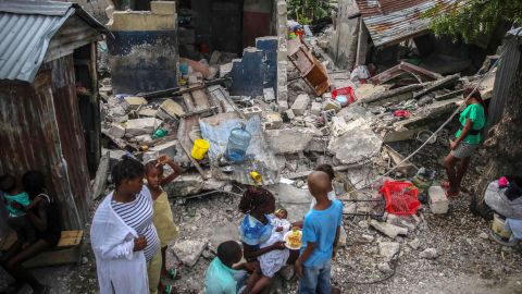 A family eats breakfast in front of homes destroyed by a 7.2 magnitude earthquake in Les Cayes, Haiti, on Sunday, August 15.