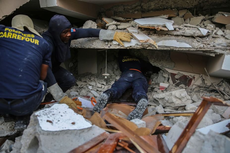 Firefighters search for survivors inside a collapsed building in Les Cayes on August 15.