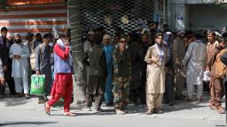 Afghans wait in long lines for hours to withdraw money, in front of Kabul Bank, in Kabul, Afghanistan, Sunday, Aug. 15, 2021. Officials say Taliban fighters have entered Kabul and are seeking the unconditional surrender of the central government. (AP Photo/Rahmat Gul)