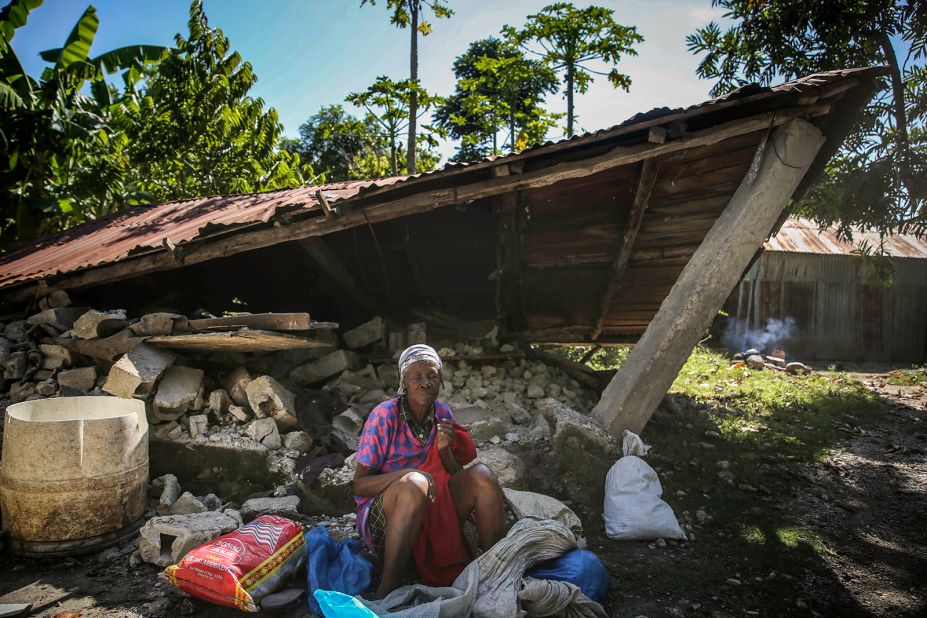 A woman sits in front of a destroyed house in Les Cayes on August 15.