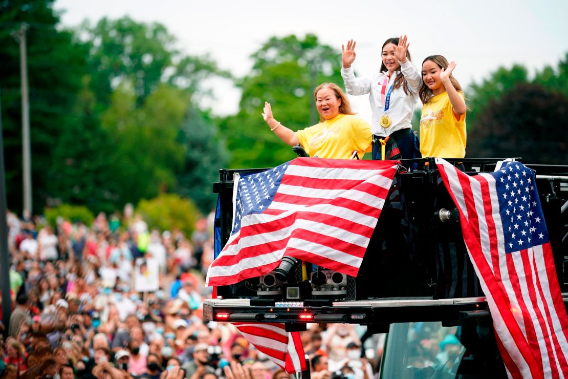 Suni Lee, center, waves from a St. Paul fire truck with her mom Yeev Thoj, left, and sister Shyenne Lee as fans cheer for her in a parade on August 8, 2021, in St. Paul, Minnesota. 