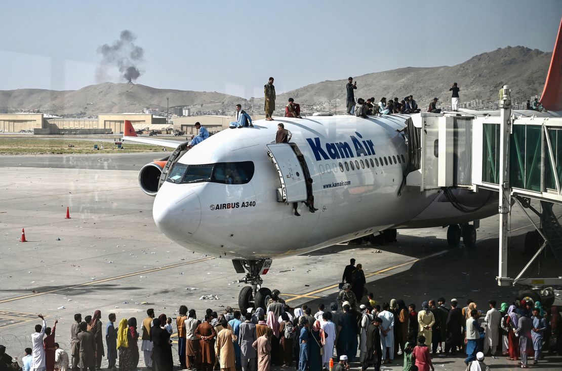 Afghans climb atop a plane amid scenes of chaos at Kabul's international airport.