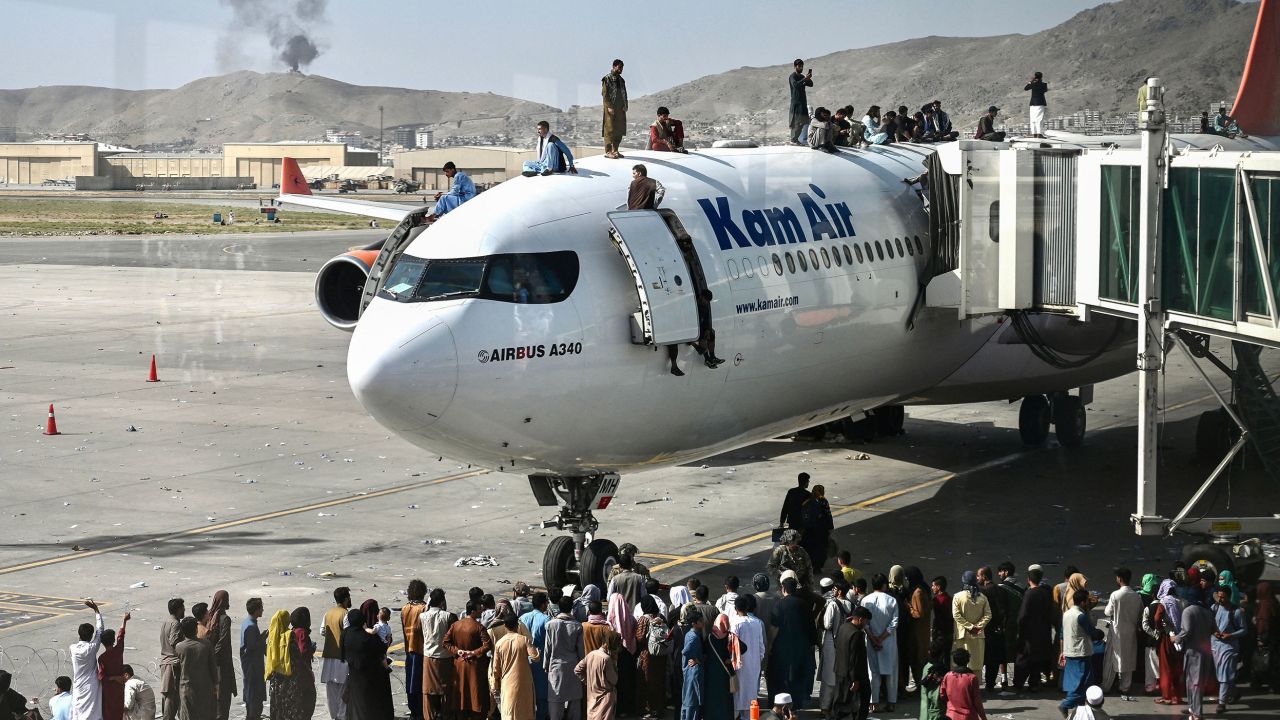 TOPSHOT - Afghan people climb atop a plane as they wait at the Kabul airport in Kabul on August 16, 2021, after a stunningly swift end to Afghanistan's 20-year war, as thousands of people mobbed the city's airport trying to flee the group's feared hardline brand of Islamist rule. (Photo by Wakil Kohsar / AFP) (Photo by WAKIL KOHSAR/AFP via Getty Images)