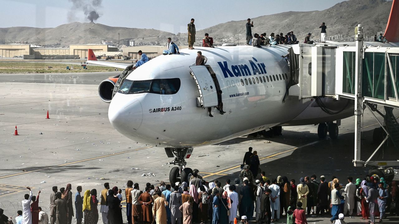 Afghans climb atop a plane amid scenes of chaos at Kabul's international airport.