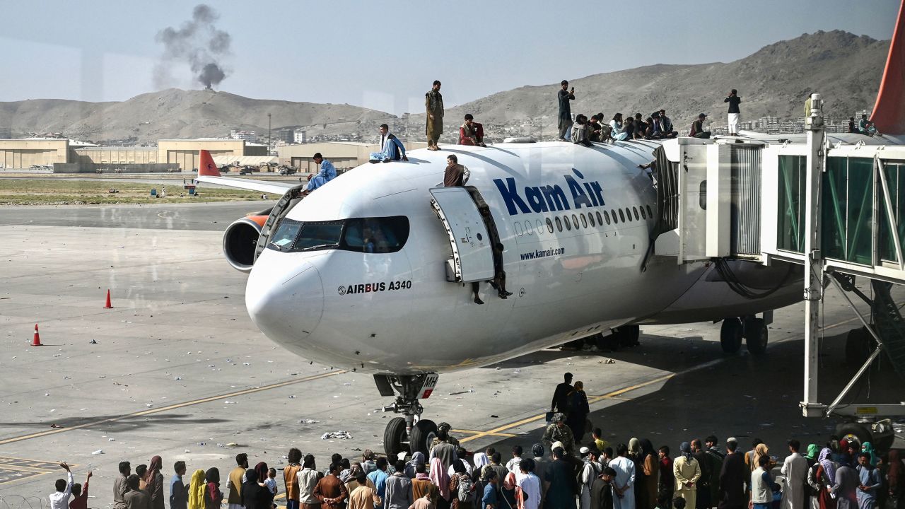 Afghan people climb atop a plane attempt to leave Kabul on Monday. The US has come under scrutiny over its hasty and chaotic withdrawal, which continued at the airport on Tuesday.