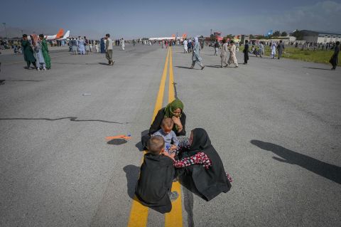 Afghans sit on the tarmac as they wait to leave the airport in Kabul on August 16.