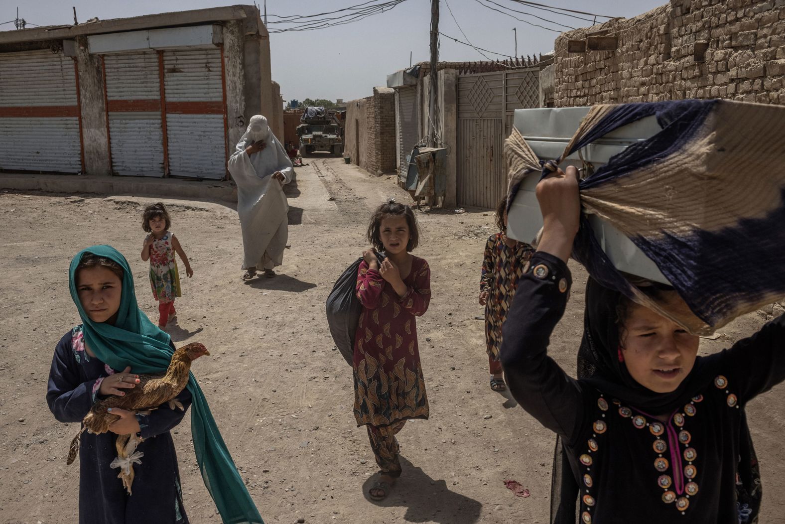 An Afghan woman and her children carry their belongings after fleeing their home in Kandahar on August 4.