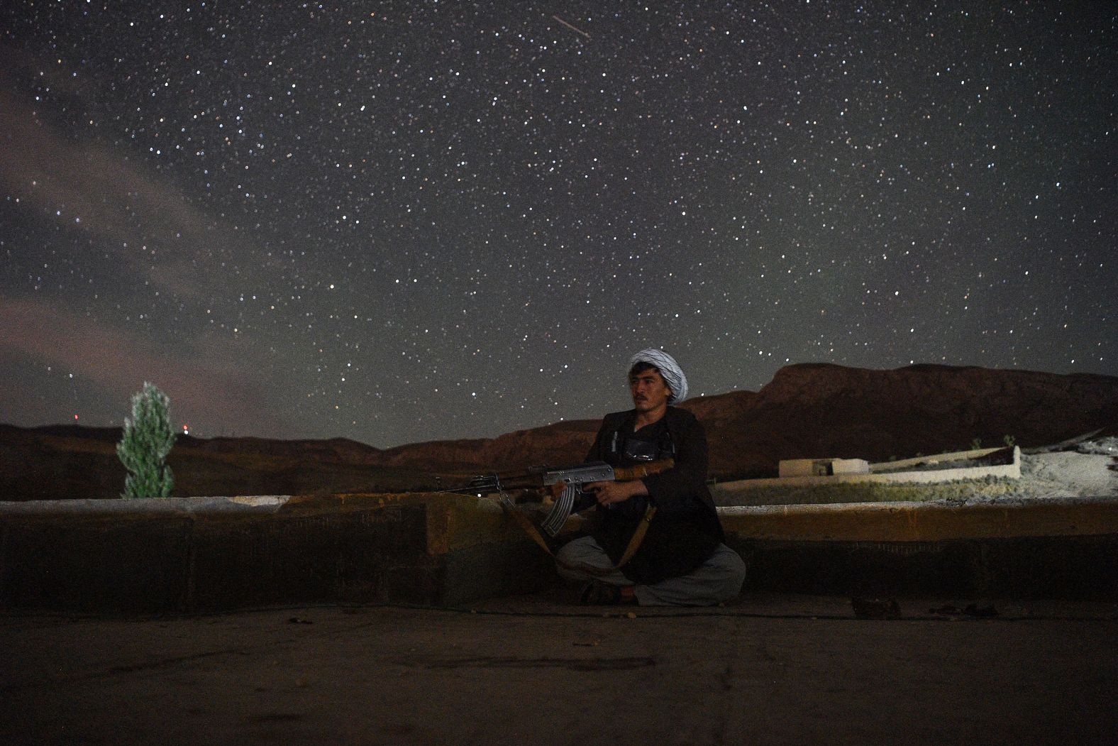 An Afghan militia fighter looks out for Taliban insurgents at an outpost in Afghanistan's Balkh Province on July 15.