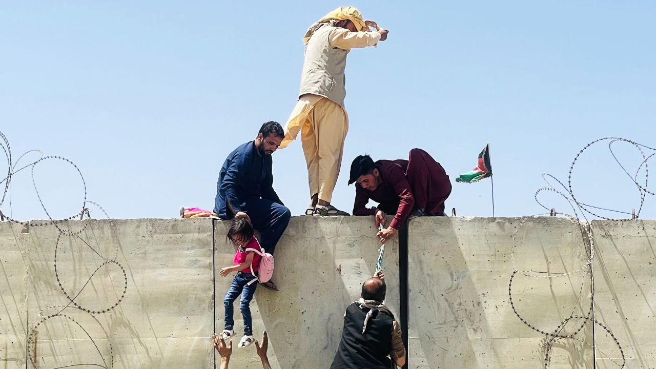 Afghans climb a wall around the Hamid Karzai International Airport during the rush to escape Kabul on Monday.