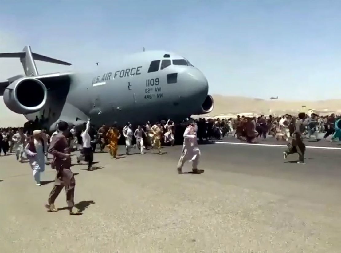 Hundreds of people run alongside a U.S. Air Force C-17 transport plane as it moves down a runway of the international airport, in Kabul, Afghanistan, Monday, Aug.16. 2021. 