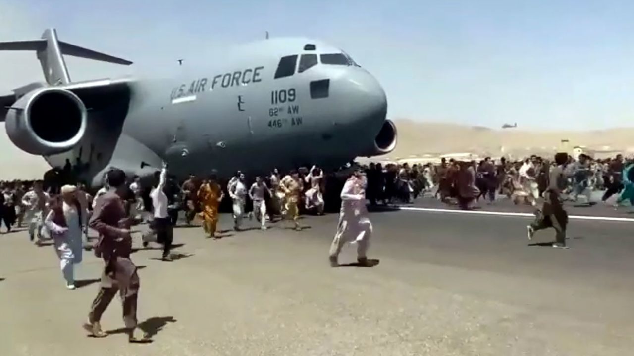 Hundreds of people run alongside a U.S. Air Force C-17 transport plane as it moves down a runway of the international airport, in Kabul, Afghanistan, Monday, Aug.16. 2021. 