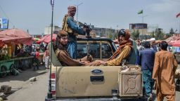 TOPSHOT - Taliban fighters on a pick-up truck move around a market area, flocked with local Afghan people at the Kote Sangi area of Kabul on August 17, 2021, after Taliban seized control of the capital following the collapse of the Afghan government. (Photo by Hoshang Hashimi / AFP) (Photo by HOSHANG HASHIMI/AFP via Getty Images)