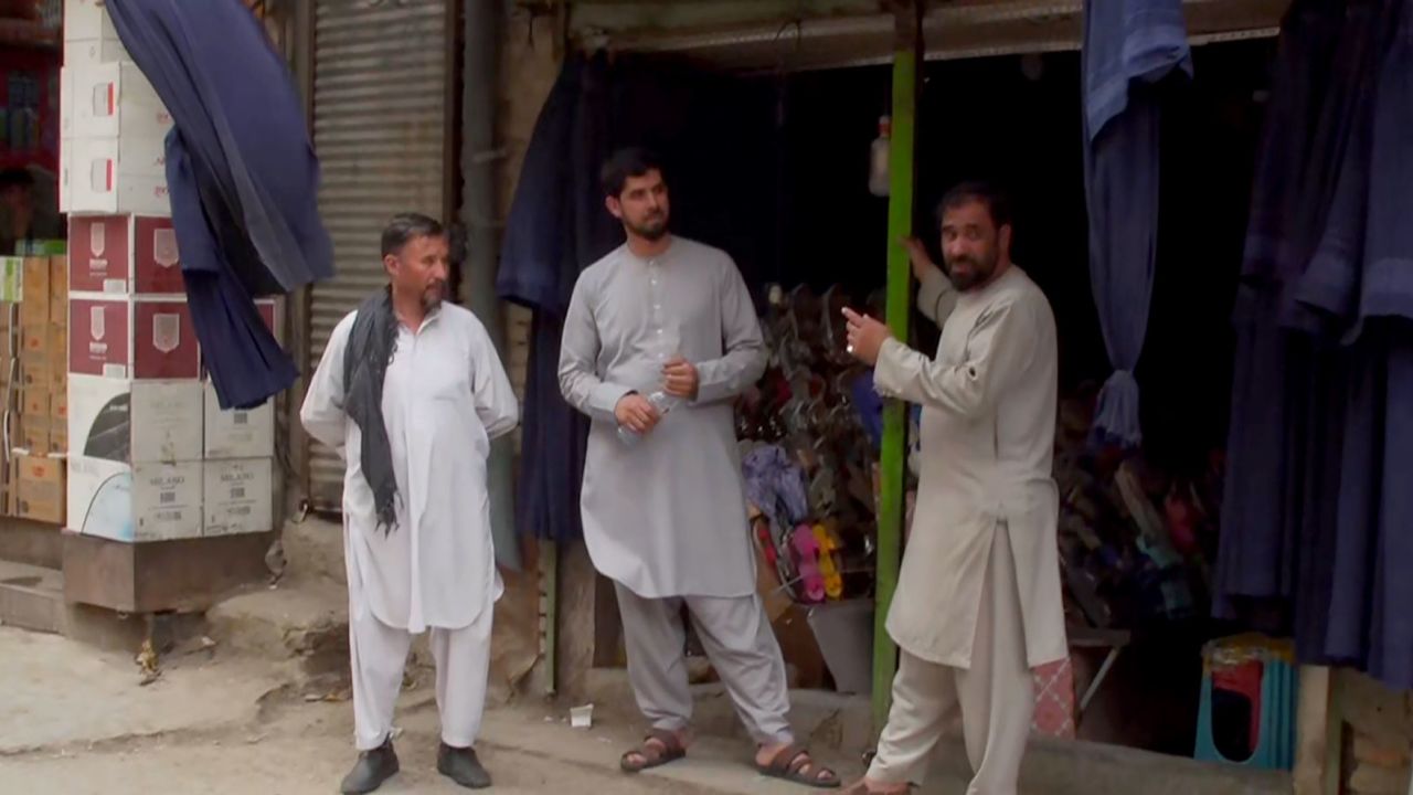 Men stand outside a clothing store in central Kabul. The store's owner told CNN he has been selling many more burqas in recent days.