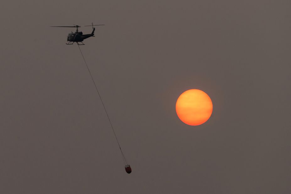 A firefighting helicopter flies in front of the sun, which was shrouded in thick wildfire smoke near Lakeview, Oregon, on August 15.