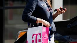 A customer carries a T-Mobile US Inc. shopping bag after leaving a retail store in Torrance, California, U.S., on Monday, Nov. 4, 2013. 