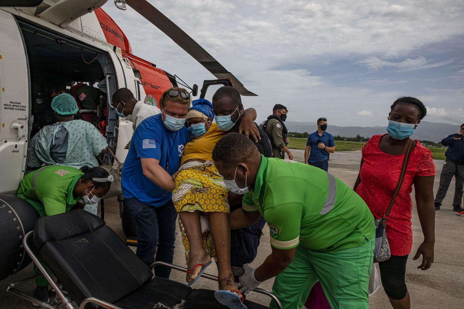 Members of the US Coast Guard assist an earthquake victim who had just arrived at the international airport in Port-au-Prince, Haiti, on Tuesday, August 17.