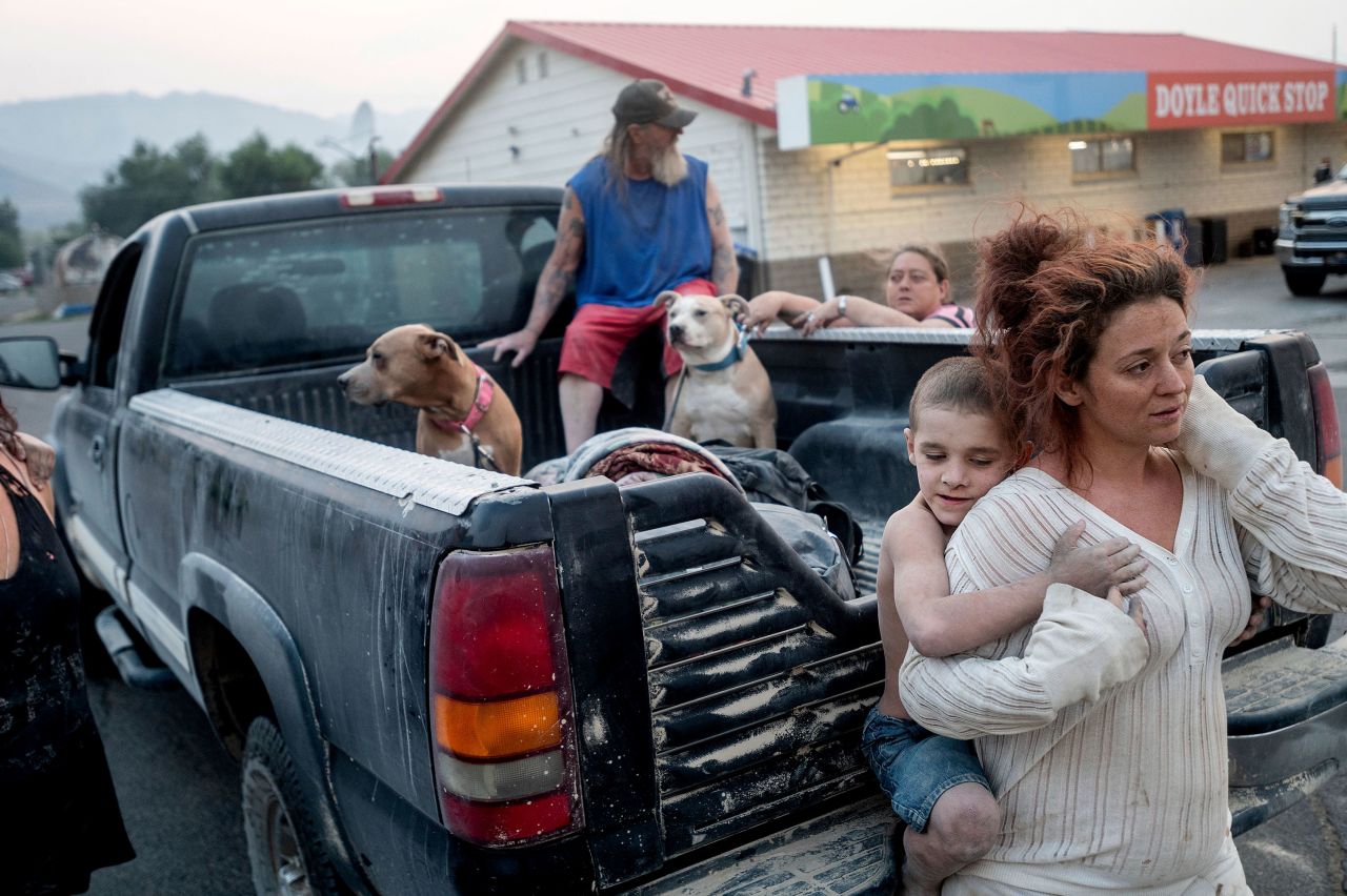 Destiney Barnard holds Raymond William Goetchius while stranded at a gas station in Doyle, California, on August 17. Barnard's car broke down as she was helping Raymond and his family flee the Dixie Fire.