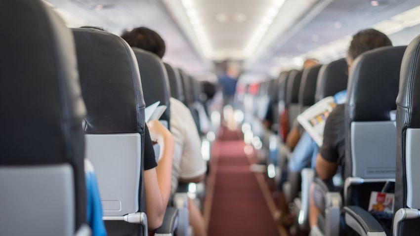 passenger seat, Interior of airplane with passengers sitting on seats and stewardess walking the aisle in background. Travel concept,vintage color