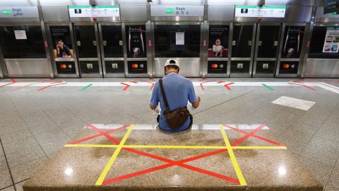 A man reading a newspaper sits on an unmarked safety distancing marker at a train station on April 21, 2020 in Singapore.