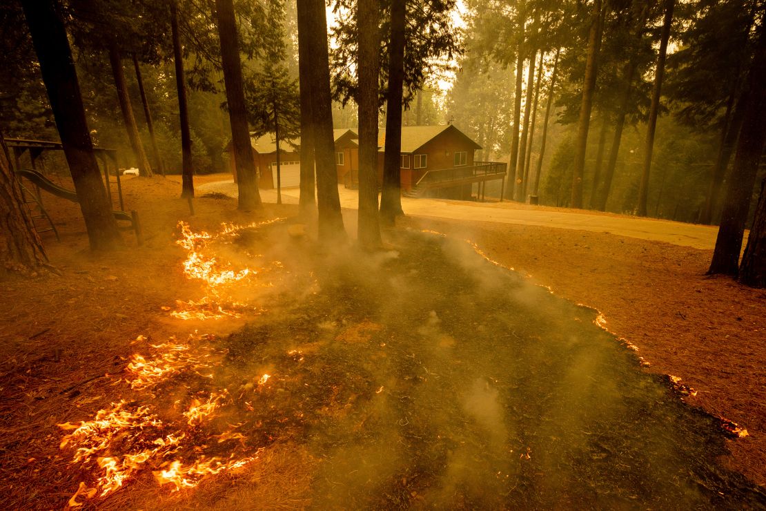 Flames from the Caldor Fire scorch the ground near a structure in Grizzly Flats, California, Wednesday, Aug. 18, 2021. 